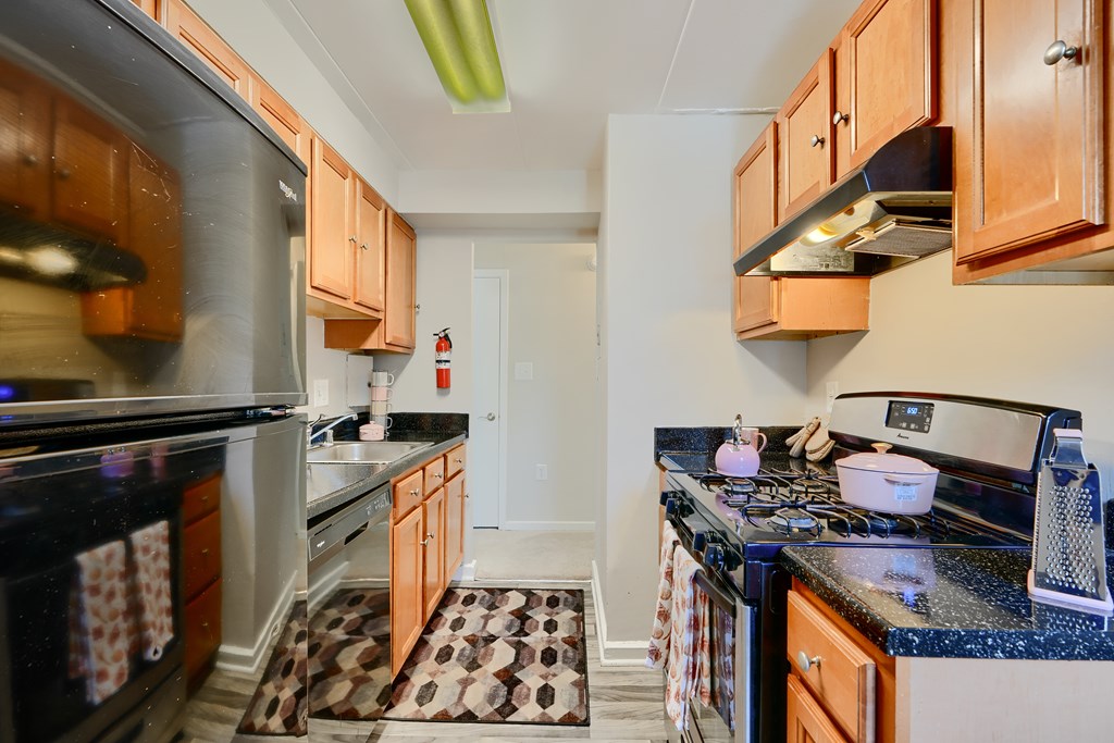 A kitchen with a black counter top and wooden cabinets.