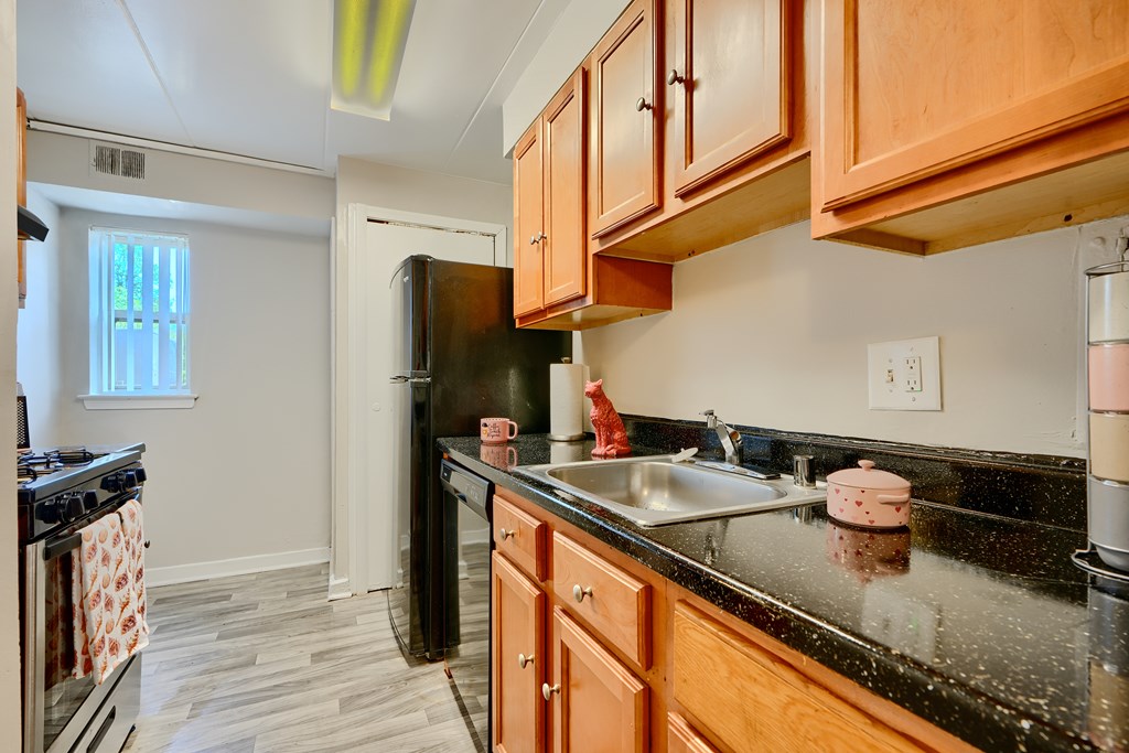 A kitchen with black countertops and wooden cabinets.
