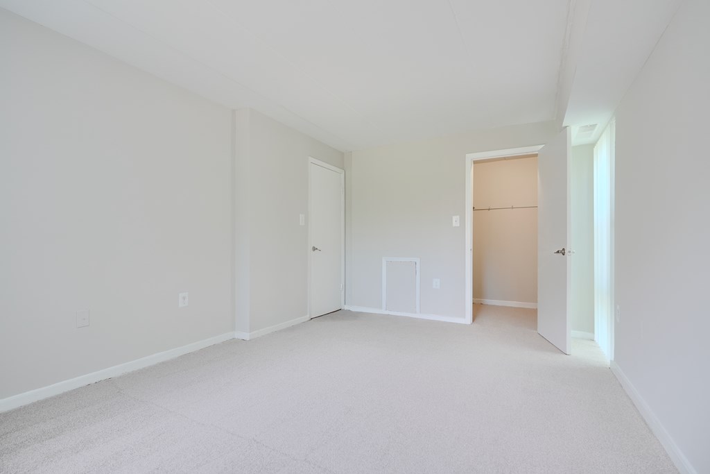 A white room with a carpeted floor and three doors.