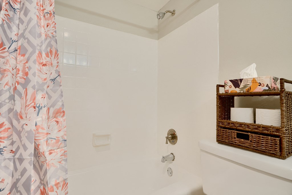 A white bathroom with a floral shower curtain.