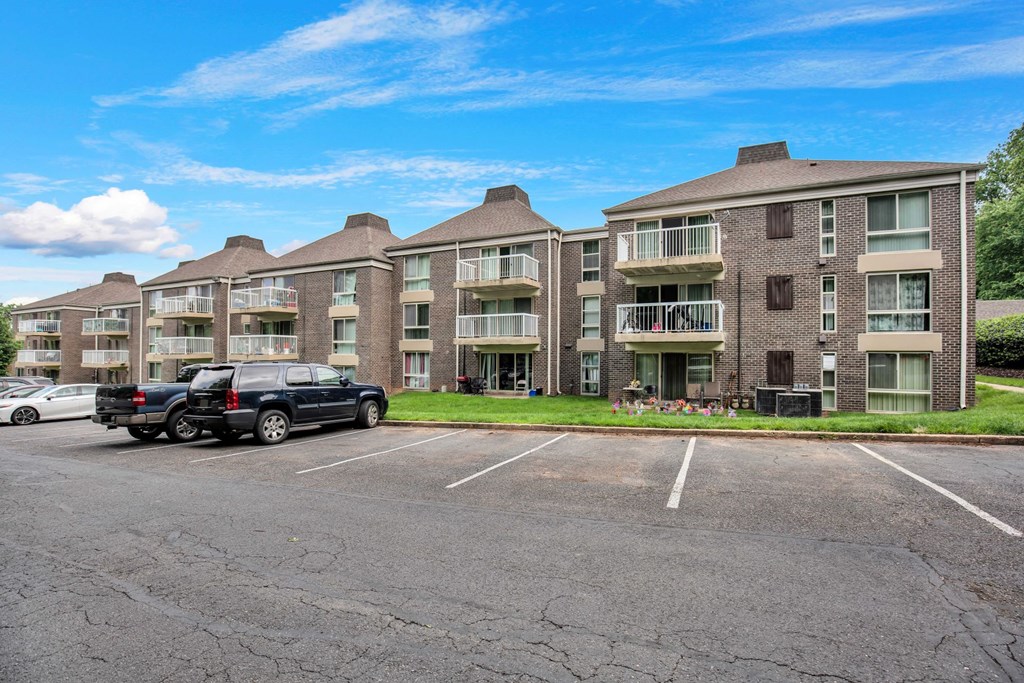 a parking lot in front of an apartment building with two cars parked in front