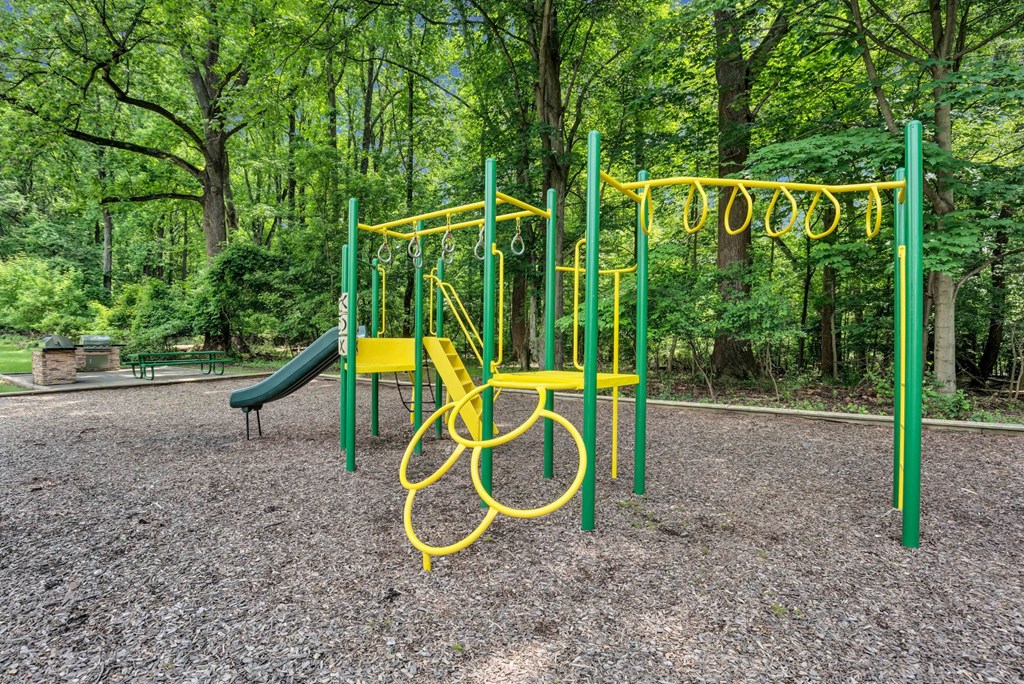 a yellow swing set in a park with trees