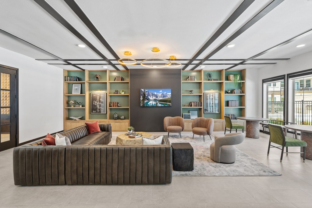 A modern living room with a large couch and a television on the wall.