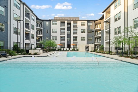 Apartment community pool featuring resort-style amenities, contemporary residential architecture, private balconies, and landscaped outdoor gathering spaces.