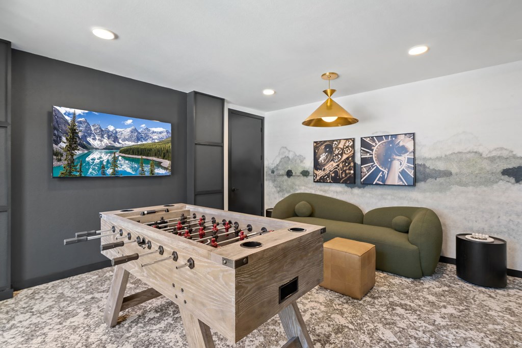 A foosball table is in the middle of a room with a couch and a TV.