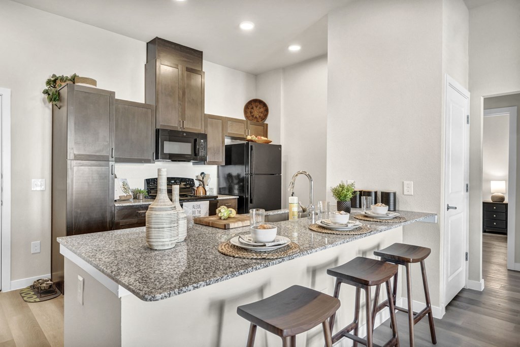 a kitchen with granite counter tops and a bar with stools