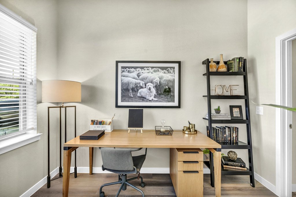 a home office with a desk and a picture of sheep on the wall