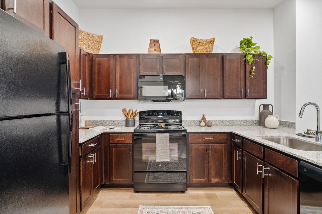 A kitchen with a black refrigerator and wooden cabinets.