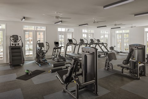 A gym with a variety of exercise equipment including treadmills, stationary bikes, and weight machines.