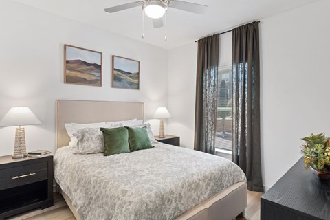 Bedroom at The Esther apartments with bed, dresser and nightstands in an open floor plan layout.