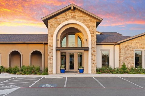 A building with a large arched entrance and a parking lot in front.