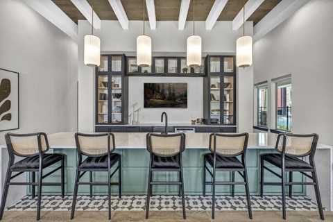 Modern resident lounge with a sleek bar, high-top seating, and elegant lighting in a bright, open space.