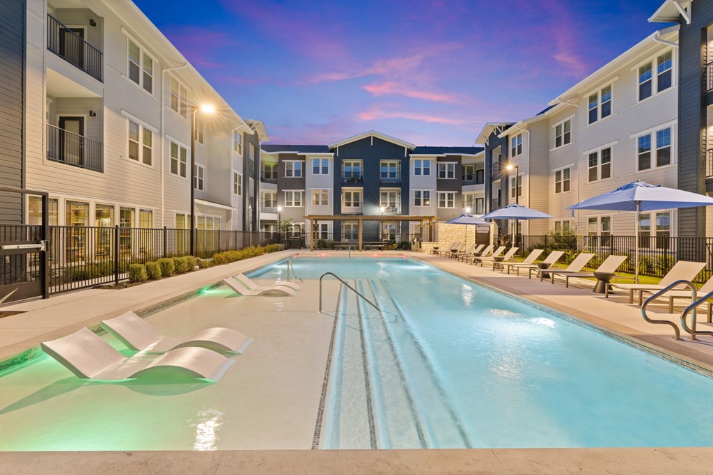 A large outdoor swimming pool surrounded by lounge chairs and umbrellas.