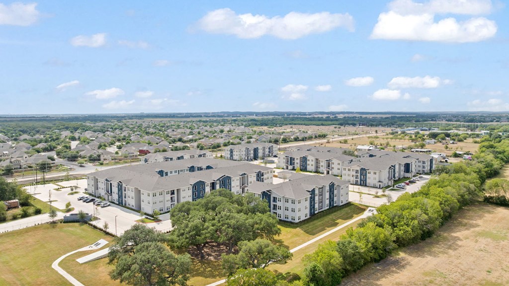 A large, modern building complex with a parking lot in front.