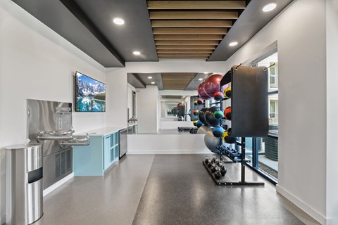 A modern kitchen with a long counter and a stainless steel refrigerator.