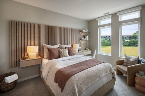 A bedroom with a large bed and a window overlooking a green landscape.