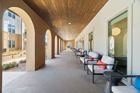 a long outdoor covered corridor with benches and chairs