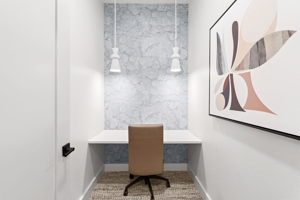 a desk with a chair in a room with a painting and a wall with lamps