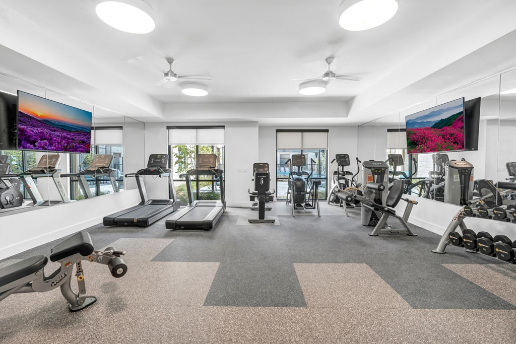 a gym with cardio equipment and televisions in a building