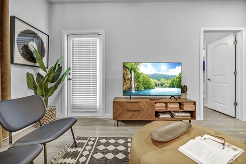A living room with a television displaying a scenic view of a lake and mountains.