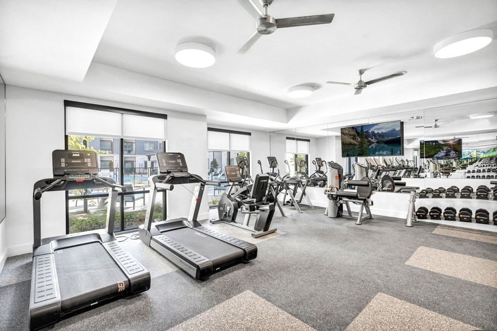 a gym with treadmills and a tv