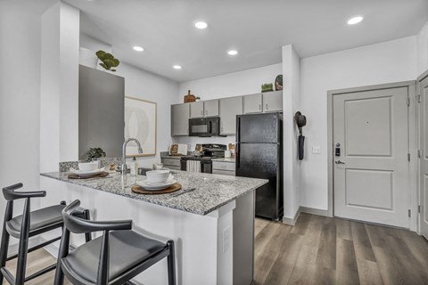 A modern kitchen with a black refrigerator and a granite countertop.