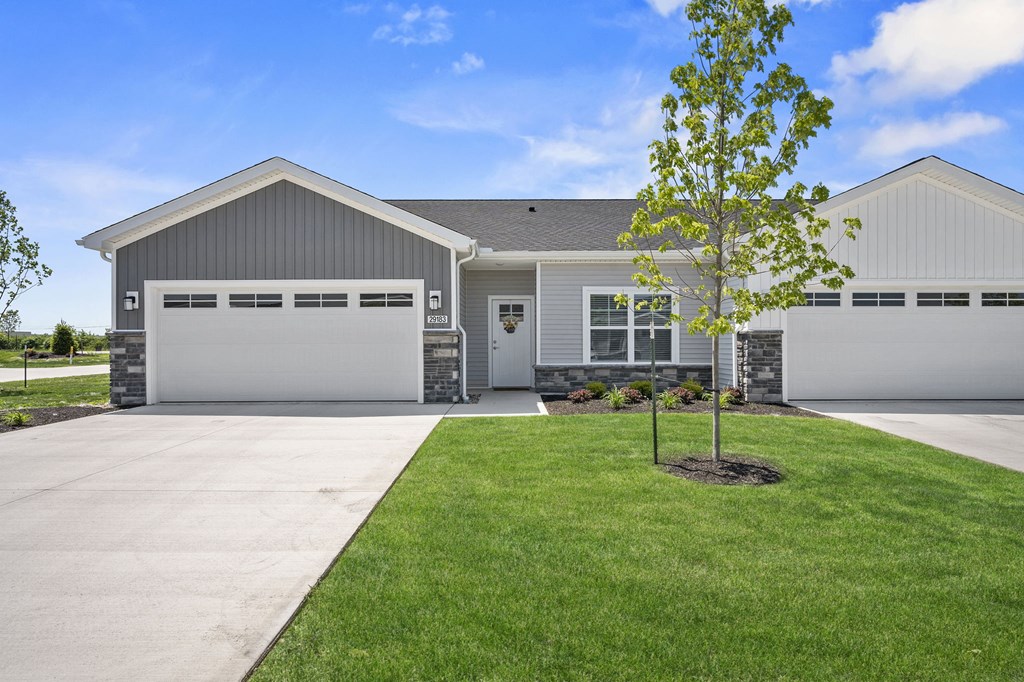 a white and gray house with a driveway and lawn