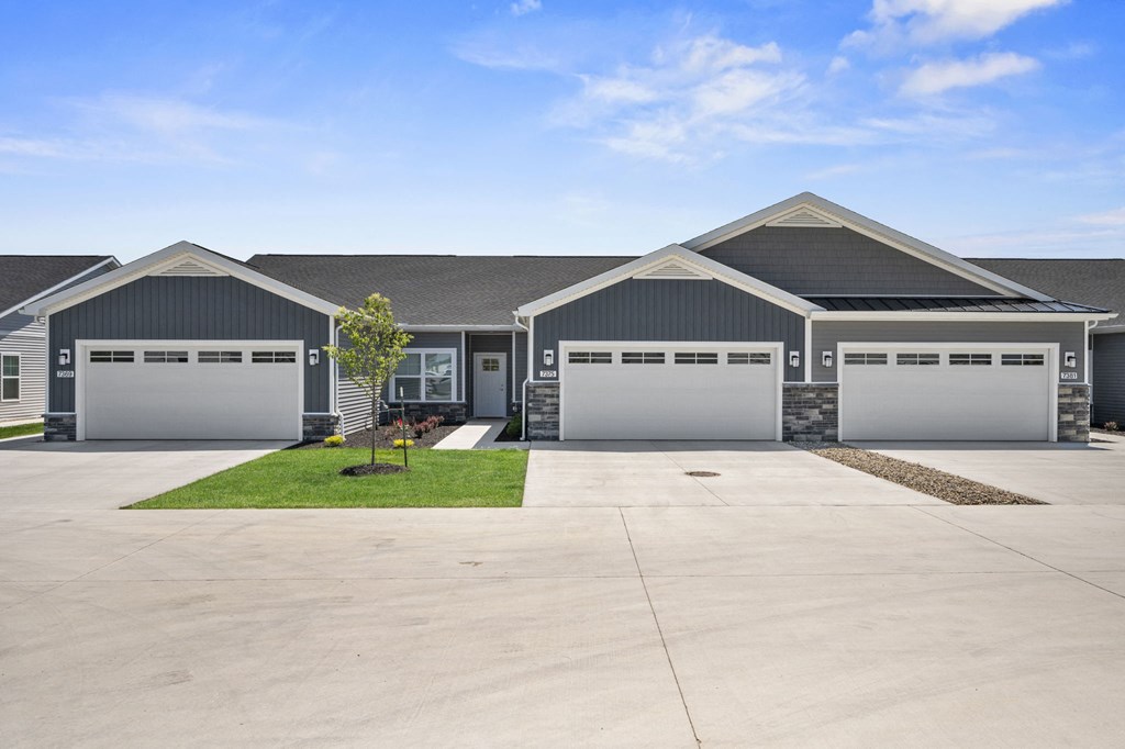 the front of a house with two garage doors and a driveway