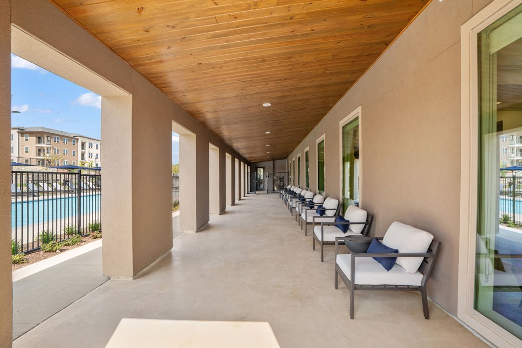 a long porch with chairs and a view of the pool