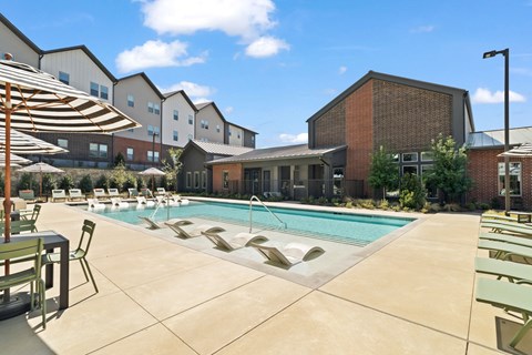 Resort-style swimming pool featuring in-water lounge seating, sun deck areas, and outdoor gathering space for residents.