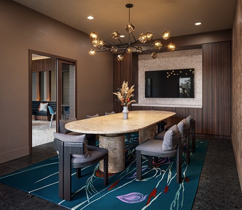 A modern room with a round table and grey chairs.