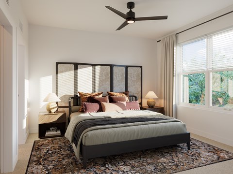 A bedroom with a large bed and a ceiling fan.