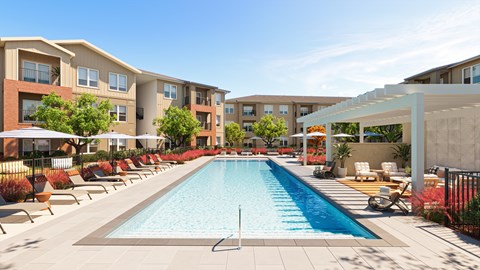 A large swimming pool is surrounded by lounge chairs in front of apartment buildings.