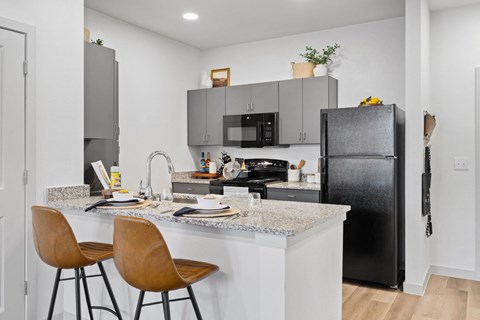 a kitchen with black appliances and a counter with bar stools
