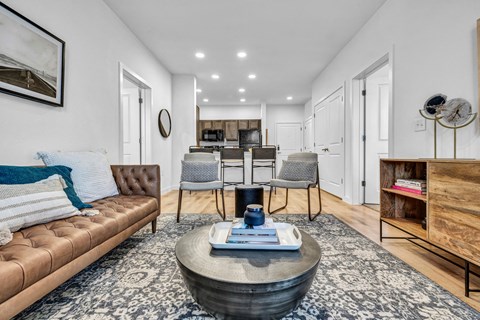 A living room with a brown leather sofa and a coffee table in the center.