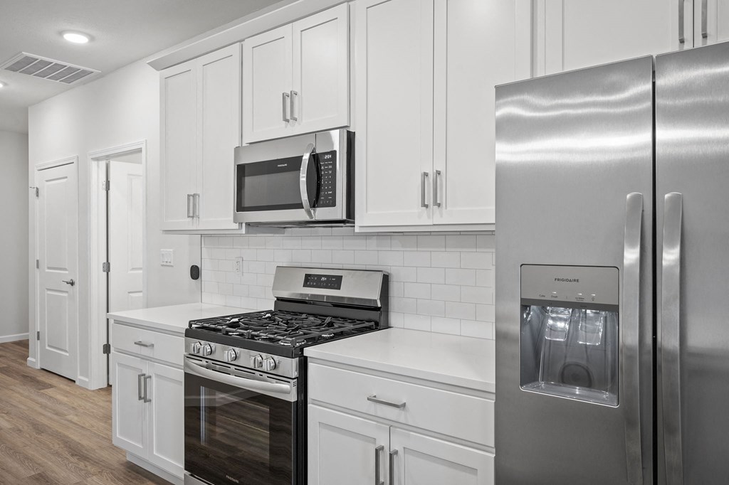 a kitchen with white cabinets and stainless steel appliances