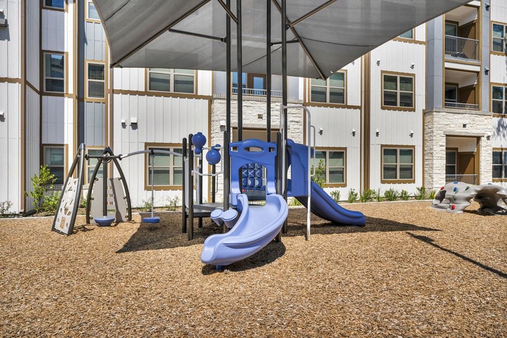 a playground with slides and swings at an apartment building