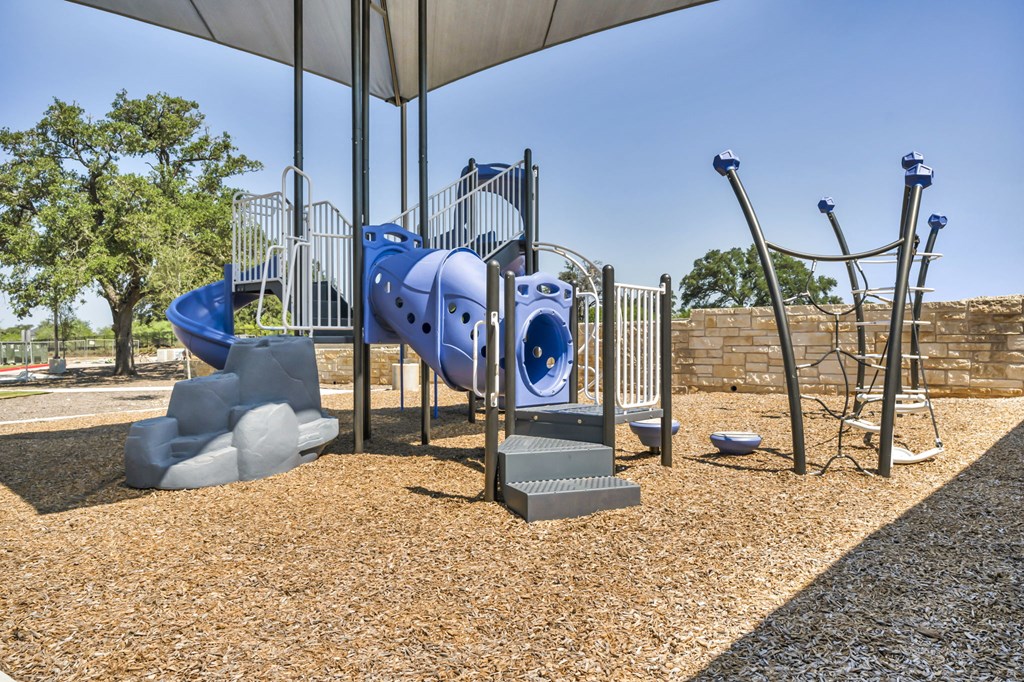 a playground with a blue slide and climbing equipment in a park