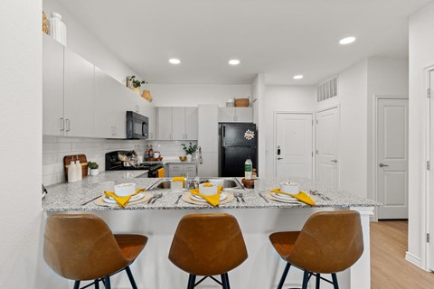 a kitchen with a marble counter top with four chairs