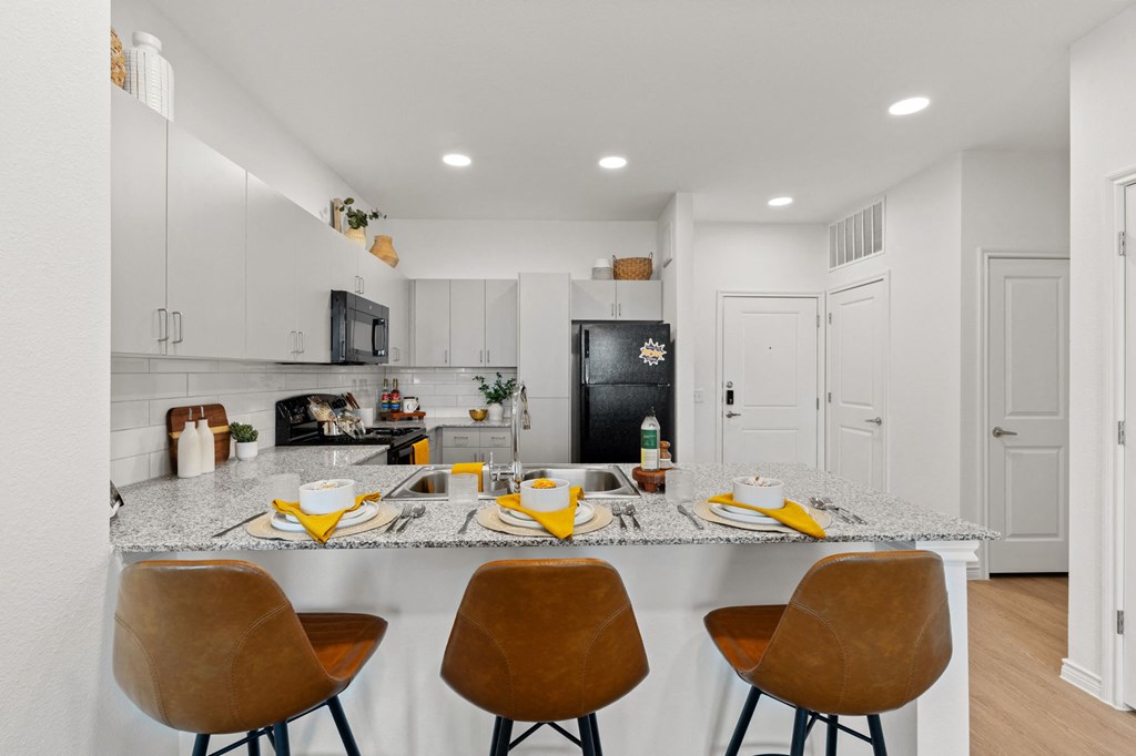 a kitchen with a counter top and a bar with four chairs