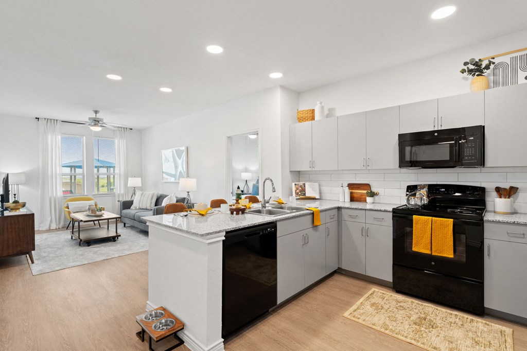 an open kitchen and living room with white cabinets and a counter top