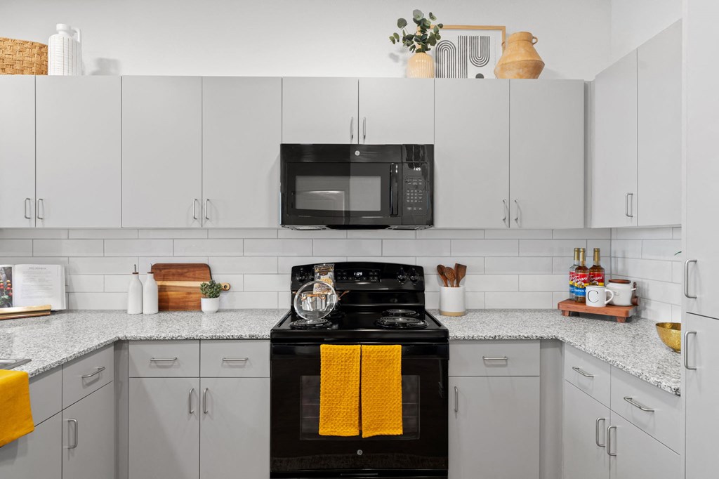 a kitchen with white cabinets and a black stove and a microwave