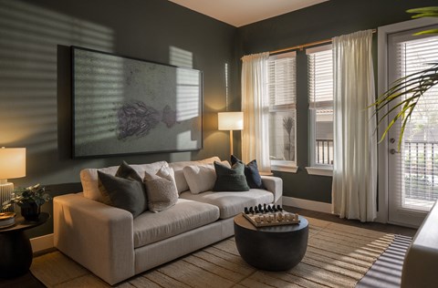A living room with a couch, a table, and a painting on the wall.