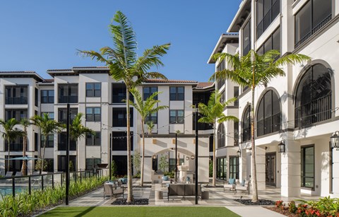 A row of modern buildings with a pool and palm trees in front.