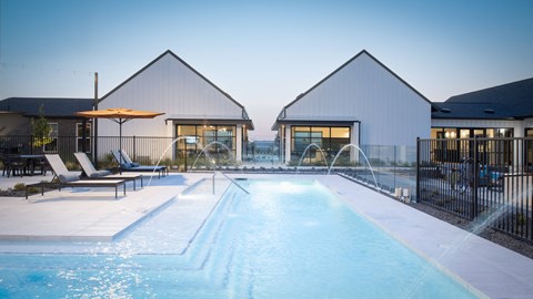 a swimming pool in front of a pool house with a water fountain
