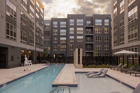 A swimming pool in front of a building with a sunset in the background.