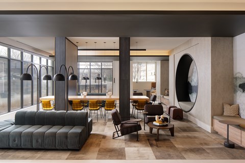 A modern living room with a large grey sofa and a round mirror on the wall.