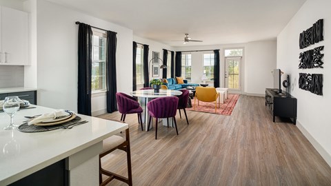A modern dining room with a white table and purple chairs.
