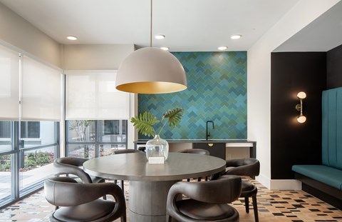 A modern dining room with a round table and grey chairs.