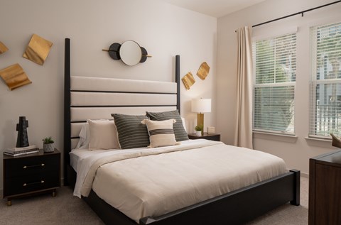A bedroom with a large bed and a window with blinds.
